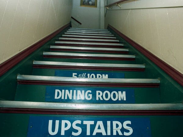 The stairs inside Lucca that read '5 till 10 p.m. dining room upstairs'.