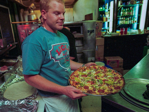 A waiter prepares to serve a pizza.