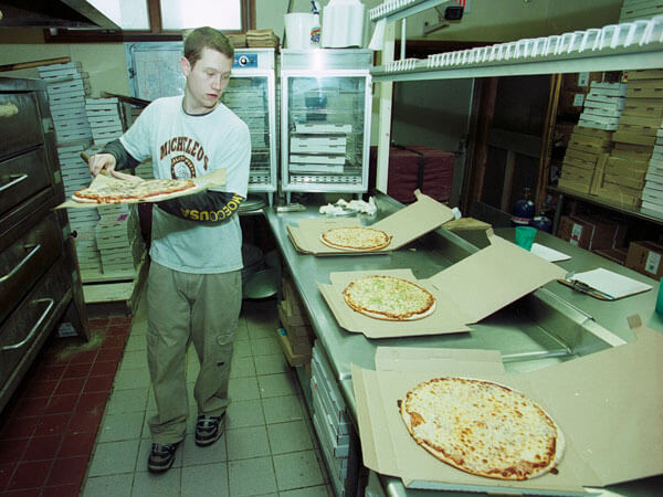 A Micheleo's employee boxes pizza.