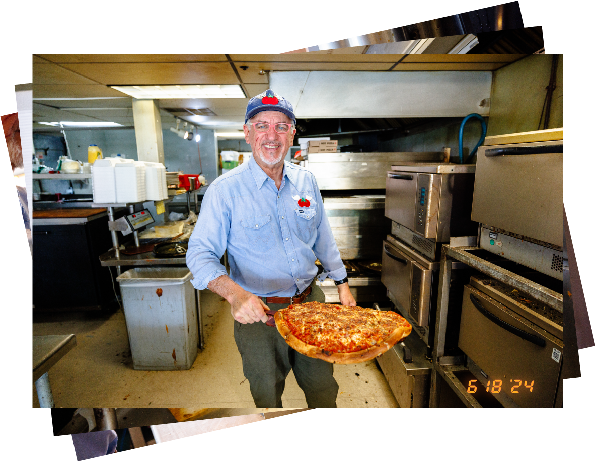 Ralph poses for a photo while holding a pizza fresh out of the oven.