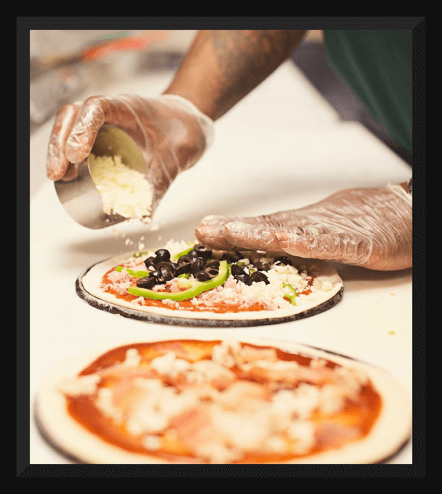 A chef puts cheese on a pizza.