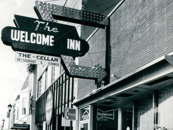 The lighted sign on the exterior of the Welcome Inn/The Cellar.