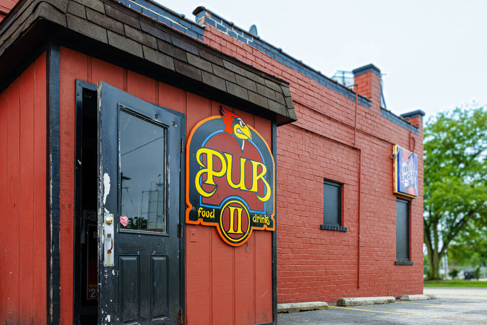 A red brick pub building with a colorful sign and a black door.
