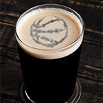 Glass of stout beer top with basketball shape on wooden background