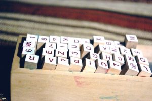 small wooden blocks with letters stamped on them sit in a wooden box