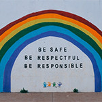 A painted wall with a rainbow and be safe, be respectful, be responsible motivational words