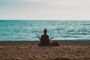 person meditating on a beach