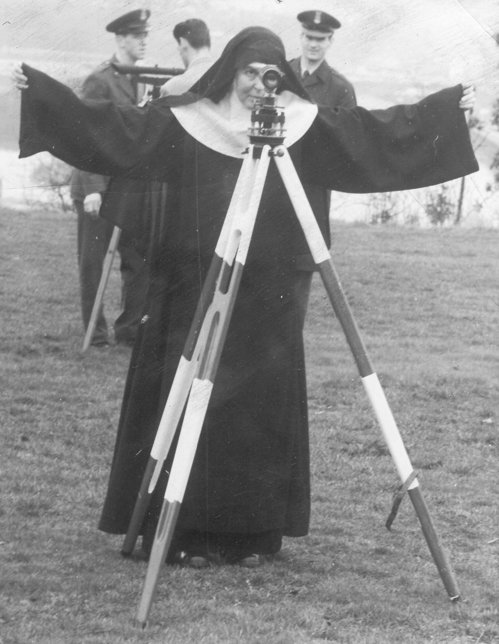 Nun in black habit using surveying equipment