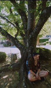 Amanda sitting cross-legged under a tree