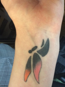 Tattoo of black and red butterfly on left wrist