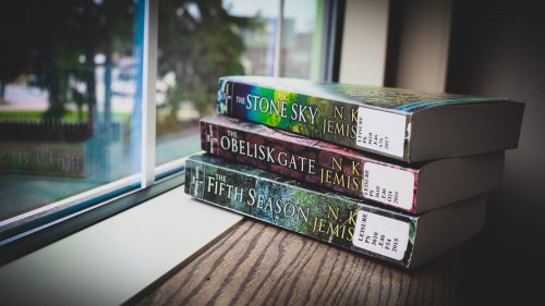 All three books in the Broken Earth trilogy are stacked on a windowsill